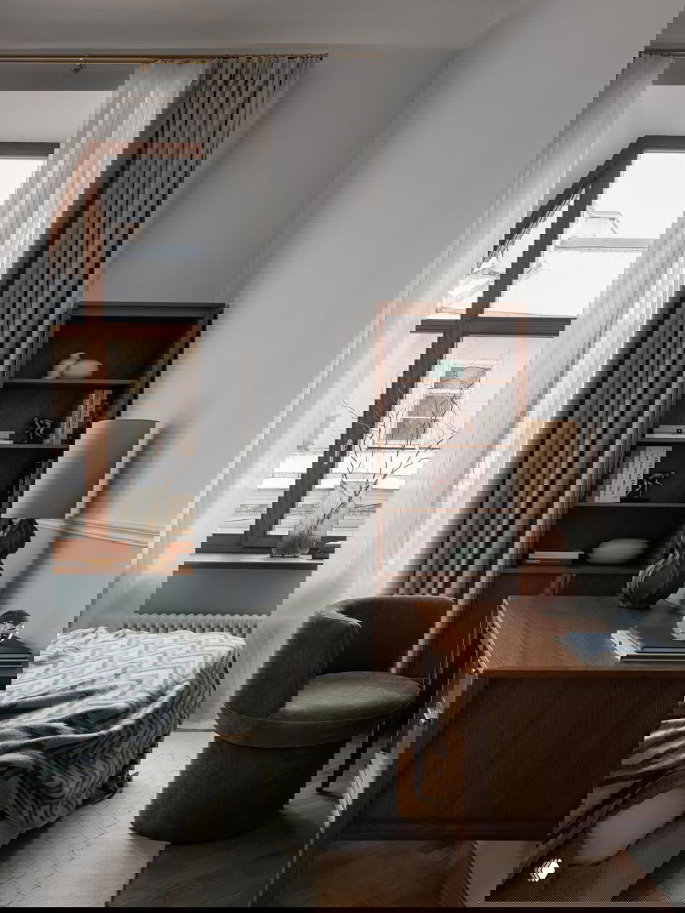 Спальня с письменным столом, высоким окном и круглым зелёным креслом у окна — сочетание деревянной мебели и мягких текстур.