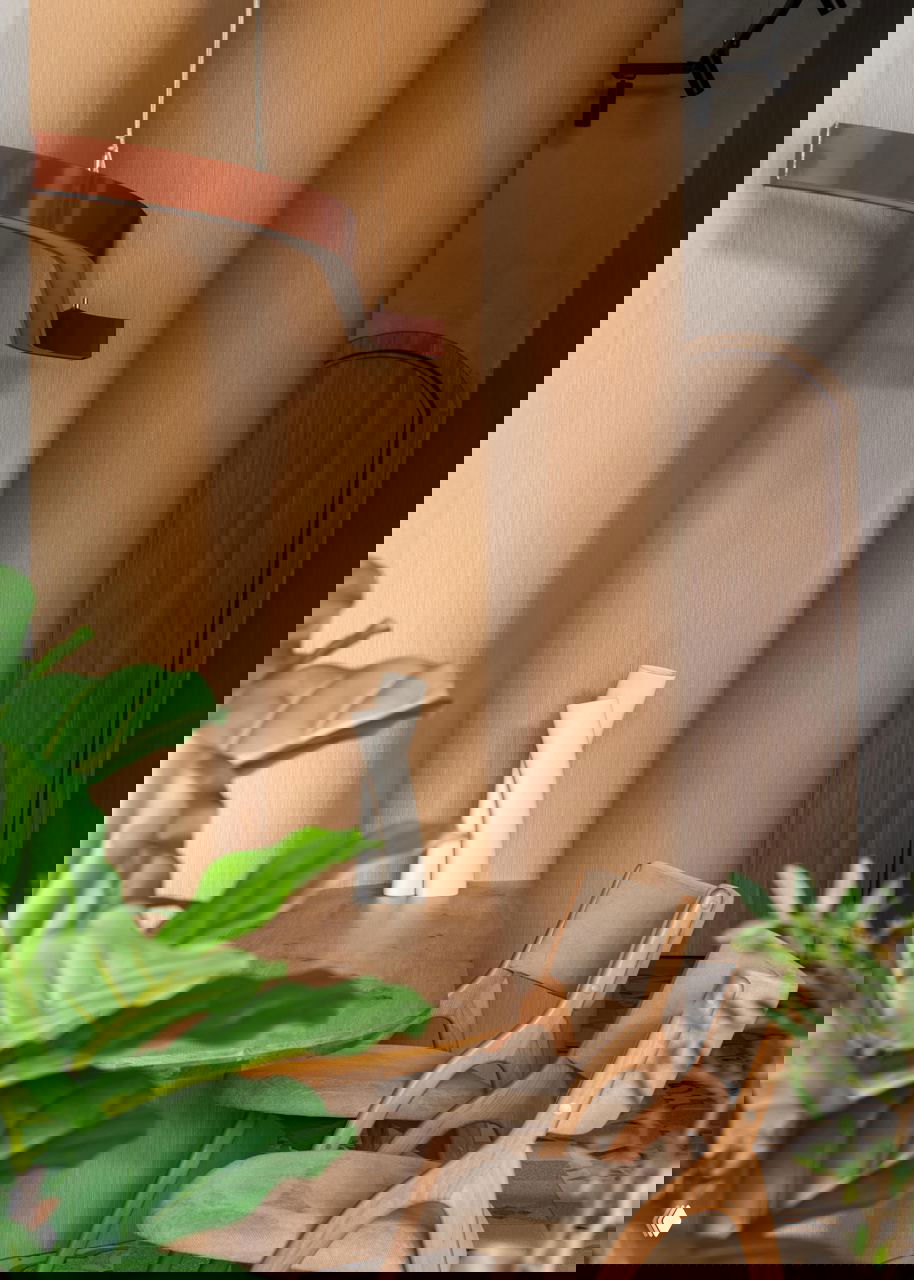 Деревянные стулья и небольшой столик у колонн, зелёные растения в кадре и детали интерьера в тёплых бежевых тонах создают домашнюю атмосферу.