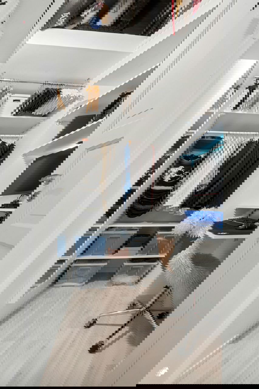 Гардеробная с открытыми полками, пластиковыми коробками для хранения и рабочим уголком; пример зонирования и систем хранения в небольшой комнате.