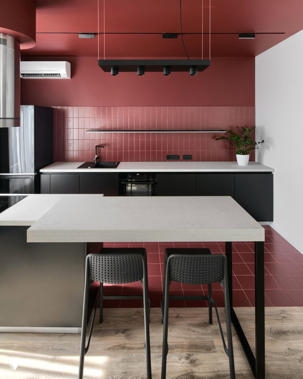 Современная кухня с чёрными низкими шкафами и насыщенными терракотовыми плитками на стене и полу; строгая линия столешницы и минимализм в оформлении.