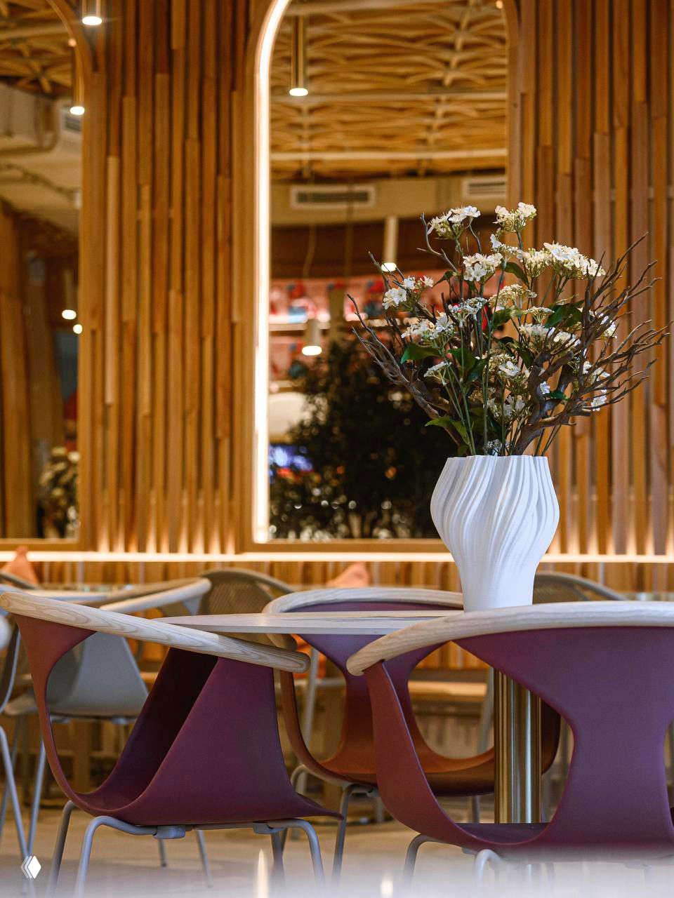Крупный план столов с декоративными вазами и бордовыми стульями Pedralli, подчёркивающими цветовой акцент интерьера и уютную атмосферу.