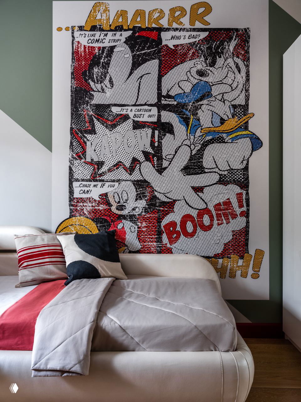 Комната с крупным графическим панно в стиле комиксов над кроватью, декоративными подушками и спокойной цветовой базой, создающей динамичный акцент в интерьере.