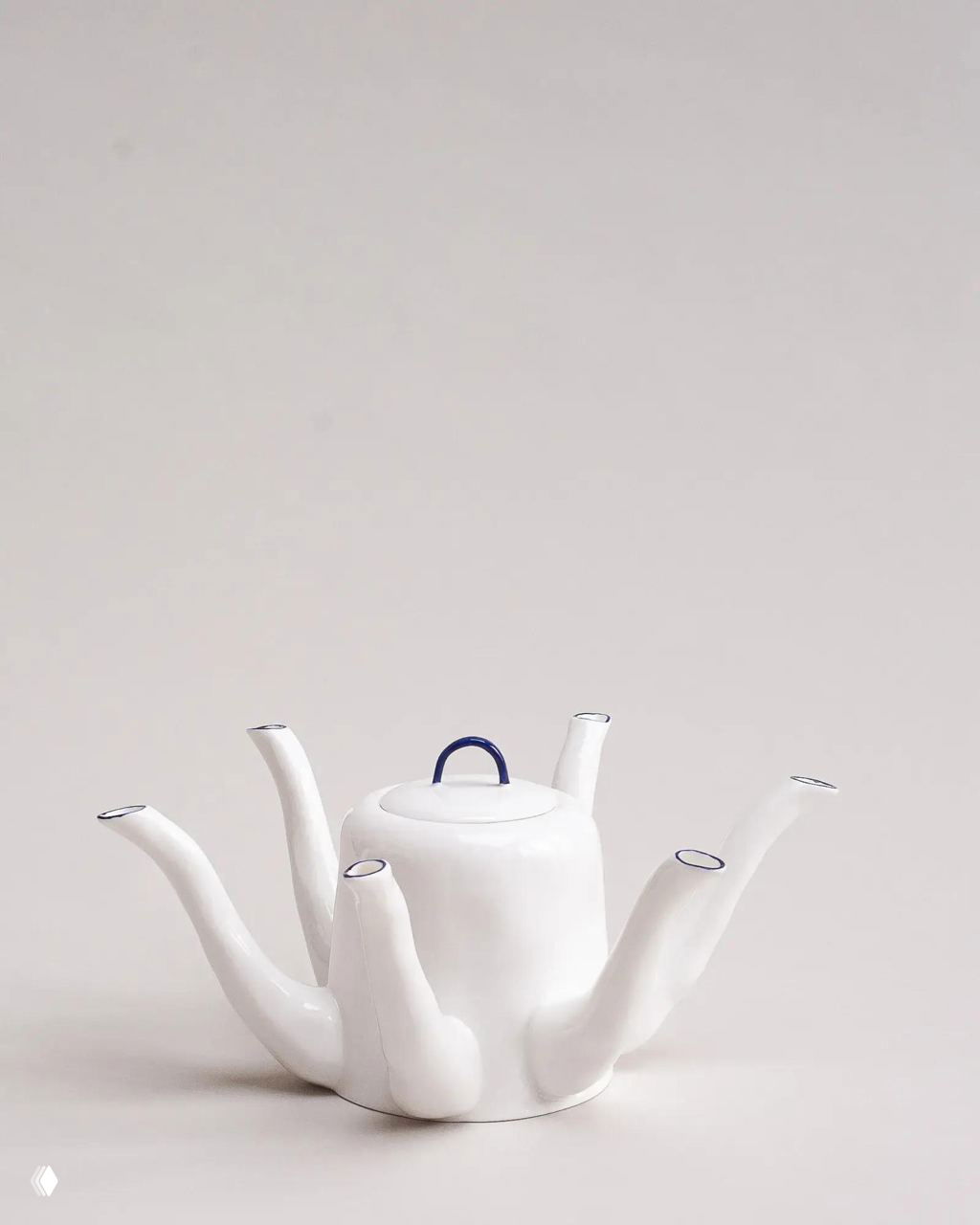 Чайник Feldspar с несколькими вытянутыми носиками, глянцевая белая поверхность и синий акцент на ручке, минималистичная композиция.