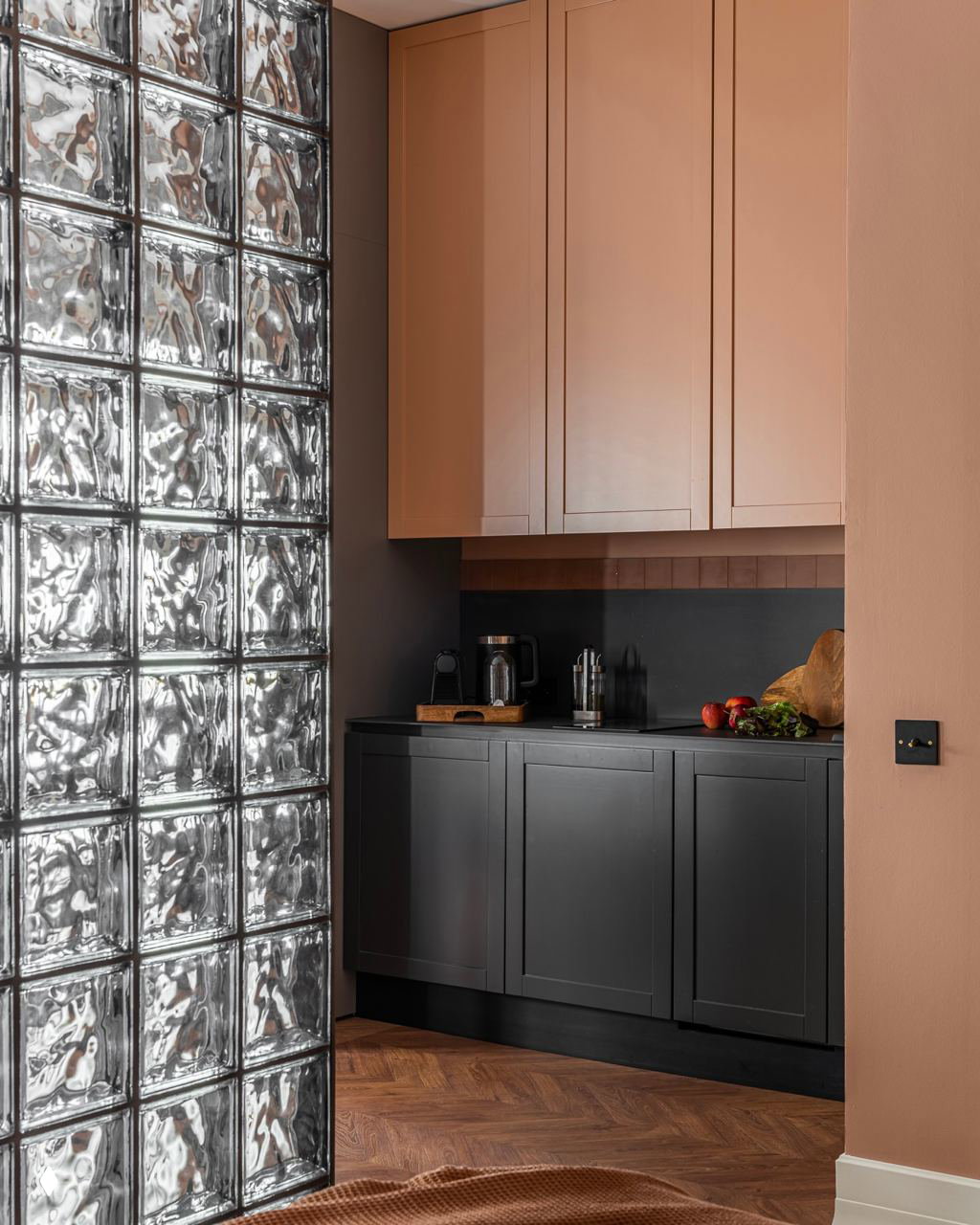 Небольшой кабинет или рабочая зона с терракотовой акцентной стеной и чёрной мебелью: сочетание тёплого цвета и строгих линий для домашнего офиса.