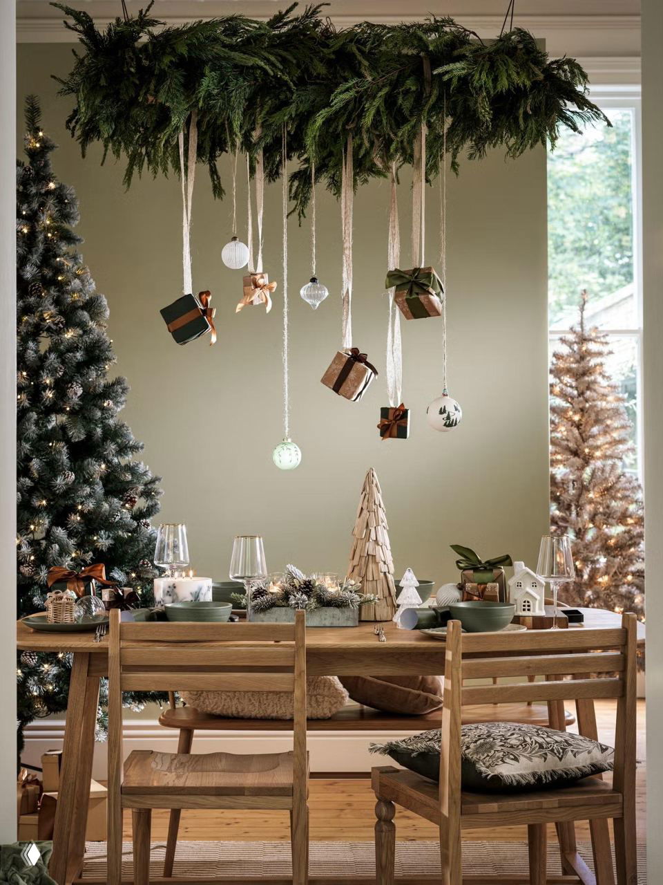 Обеденный стол в скандинавском стиле под хвойной инсталляцией на потолке: подвесные подарки, стеклянные шары на ленточках и уютная атмосферная сервировка.