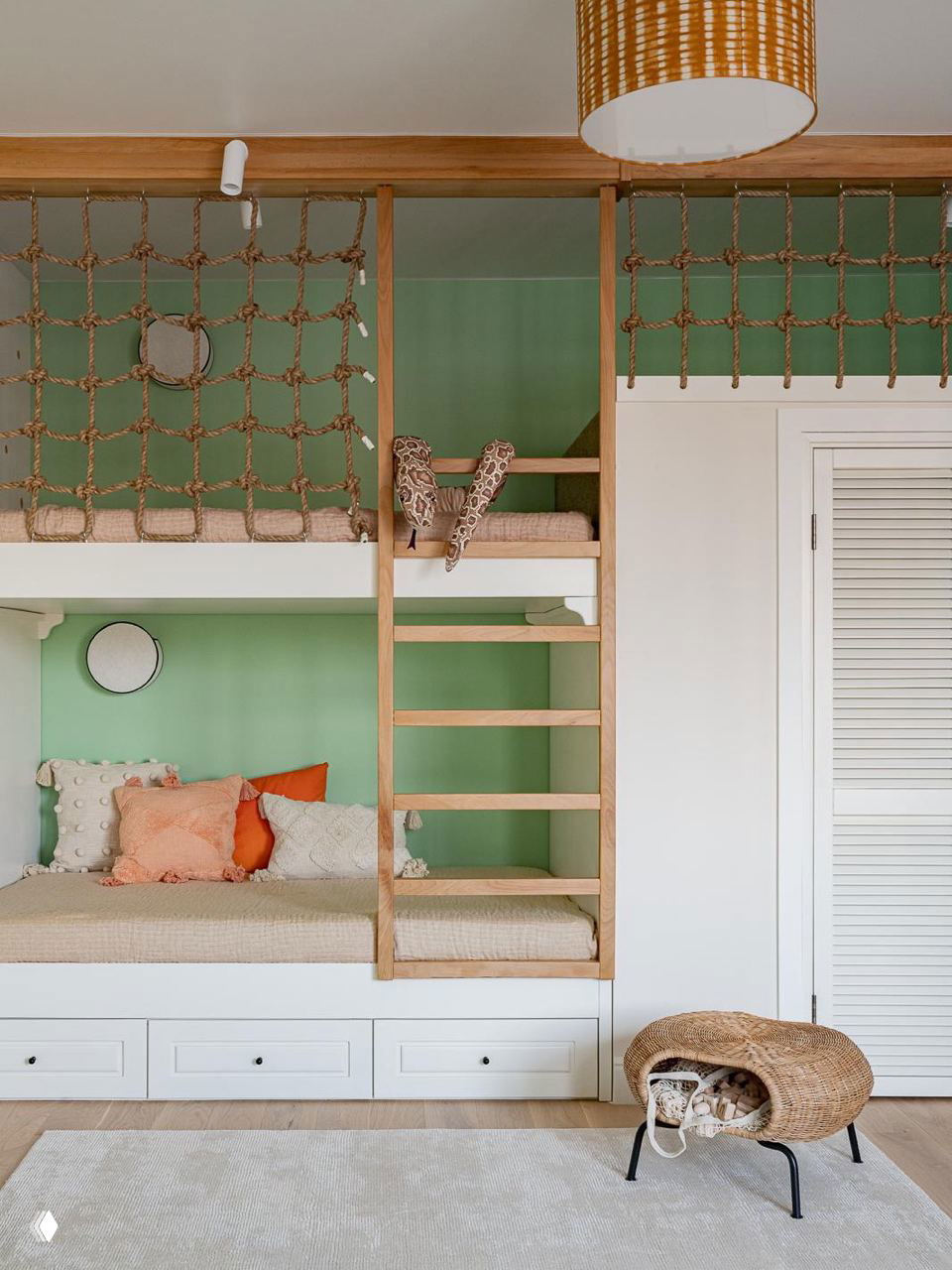 Функциональная двухъярусная система со школьной сеткой и лестницей, зелёной стеной, аккуратными выдвижными ящиками и корзиной с игрушками на светлом текстильном покрытии.