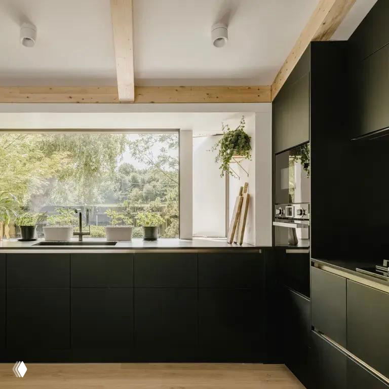 Кухонное окно в плавучем доме: тёмные фасады кухни, широкое окно и вид на зелёный берег канала, интерьер в современном скандинавском стиле