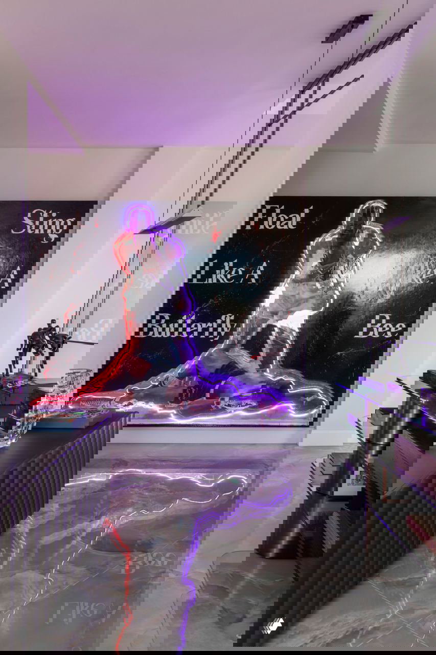 Современное арт-изображение с неоновой подсветкой и крупным полотном на стене, отражающееся в полированном ониксовом покрытии пола римской квартиры.