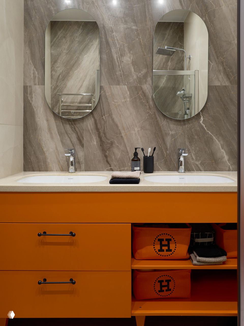Ванная комната с ярко-оранжевой тумбой под раковиной и зеркалами на серой мраморной стене, сочетание практичности и цветового акцента в компактном пространстве