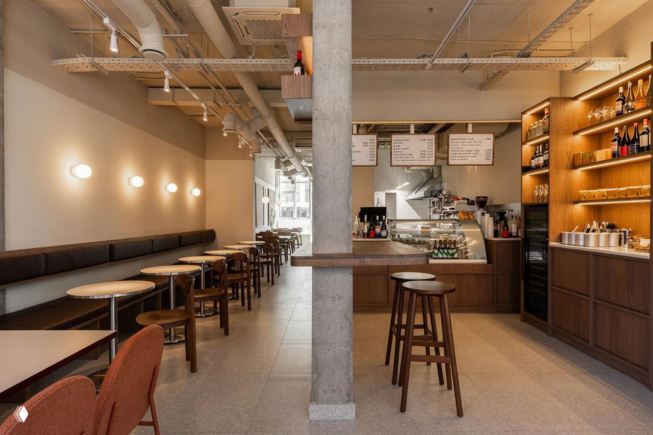 Общий план зала бистро Buno: длинная посадочная зона, бетонная колонна и открытое пространство с мягким освещением и натуральными фактурами.