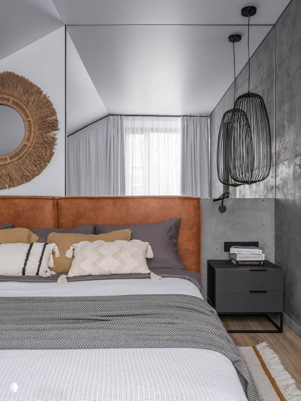 Спальня на мансарде: кожаное или текстильное изголовье тёплого оранжевого оттенка, серая бетонная стена и мягкие текстуры — уютный контраст тонов и материалов