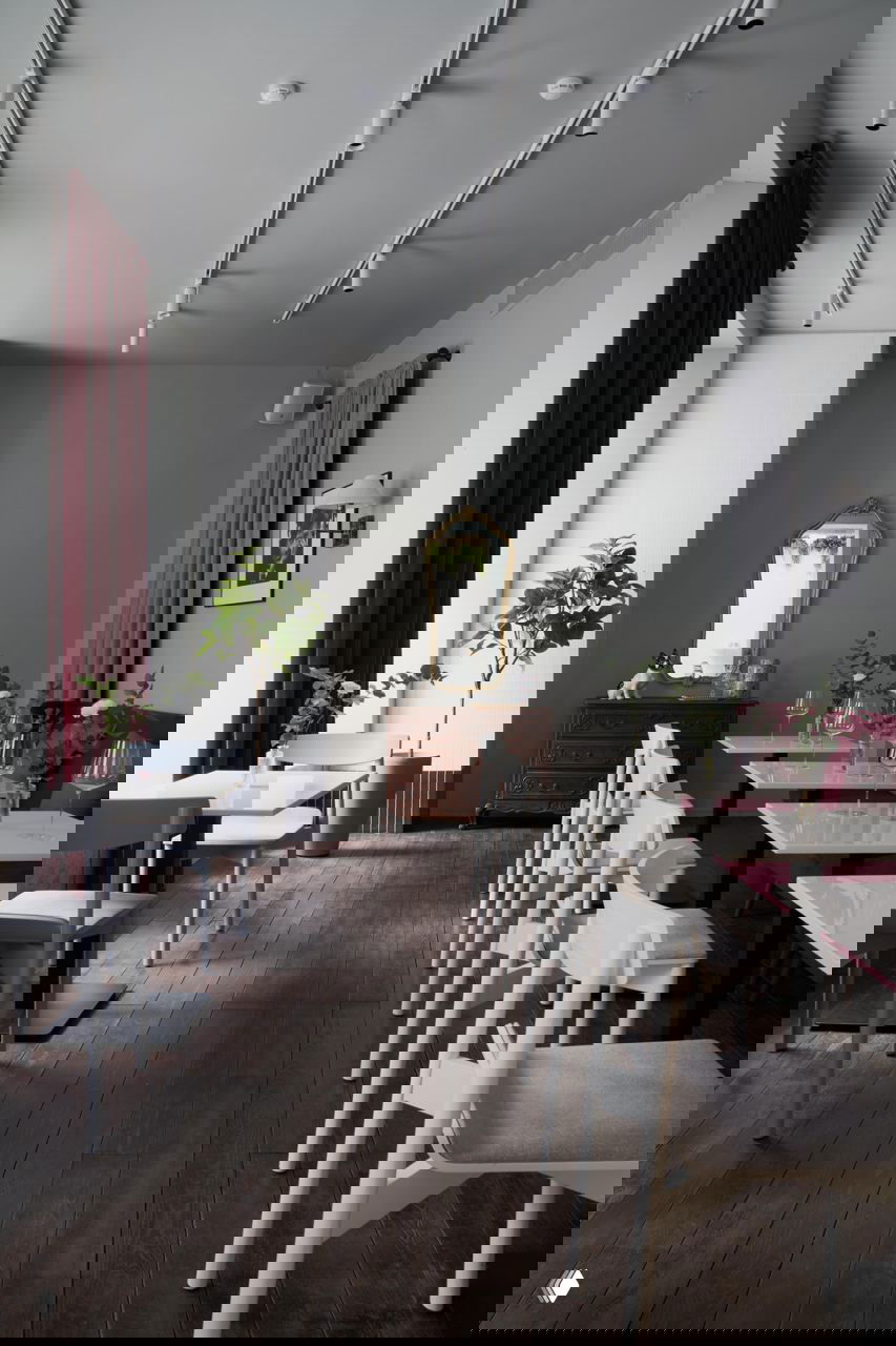 Светлый зал кафе с рядом столов и белыми стульями, тёмный деревянный пол и винтажный комод у стены создают контраст лаконичности и роскоши.