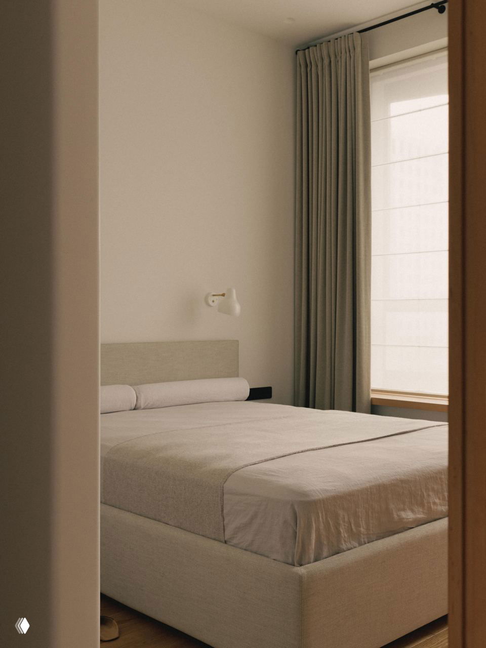 Спальня в нейтральных тонах: низкая кровать с однотонным текстилем, плотные шторы и мягкая сдержанная цветовая гамма в интерьере джапанди.