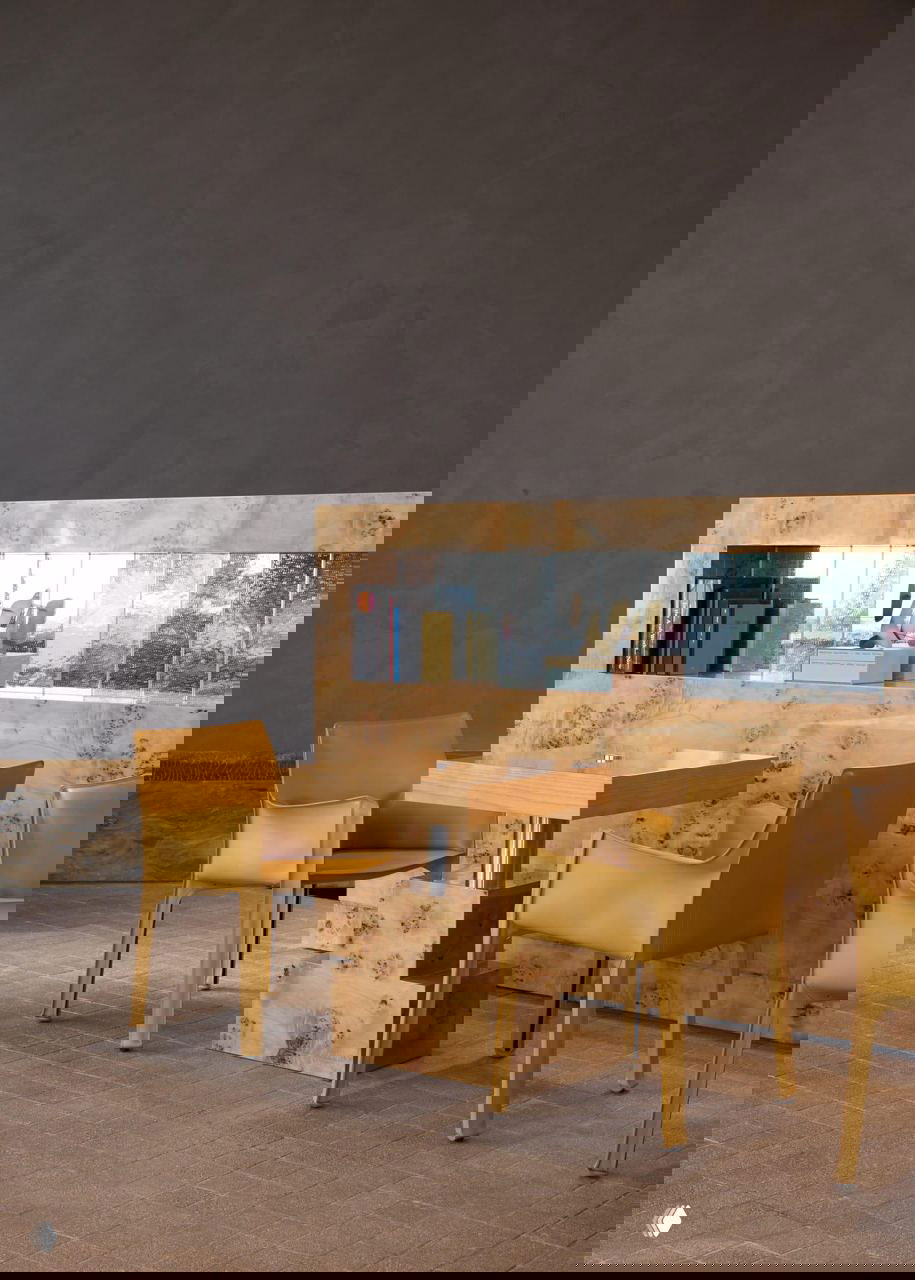 Обеденная зона с деревянным столом и жёлтыми стульями, зеркальная ниша и текстурная отделка стен и пола в интерьере кафе Daily Press.