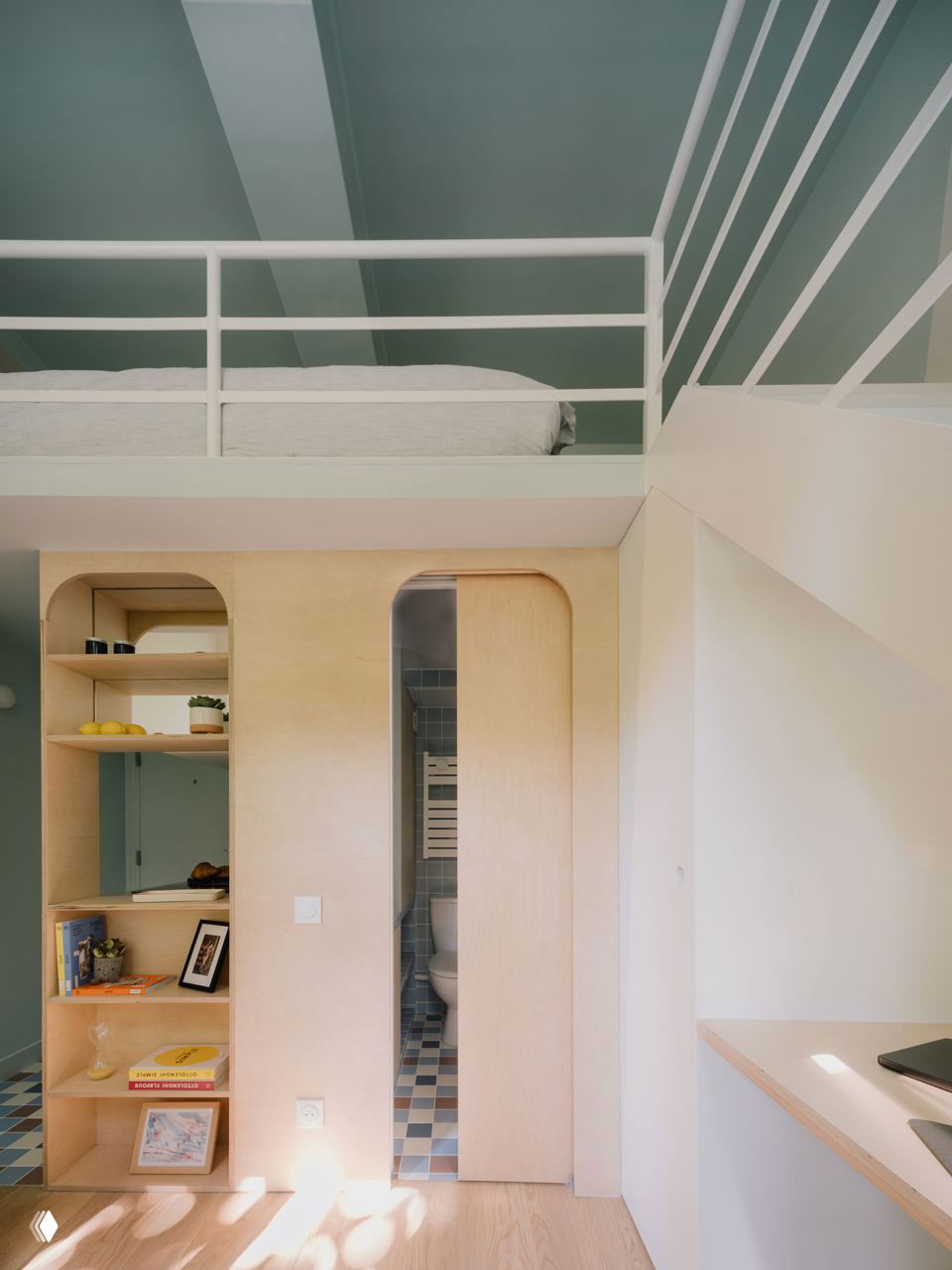 Фрагмент интерьера с видом на лестницу и белую перильную конструкцию, диагональная раскраска потолка и светлые деревянные ступени, усиливающие чувство высоты помещения.