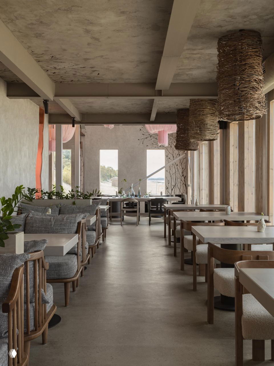 Просторный зал ресторана: ряд столов и мягких диванов у больших окон, светлые натуральные материалы, бетонный пол и спокойная палитра, вид на пляж.