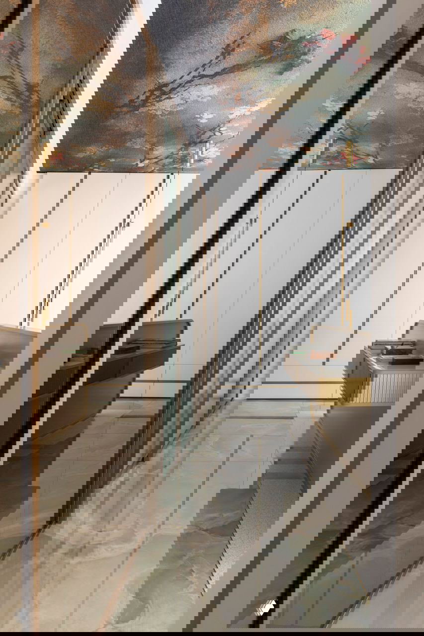 Узкий коридор и отражающие поверхности: пол из гватемальского оникса и зеркальные вставки, декоративный потолок с живописным узором и золотистыми акцентами.