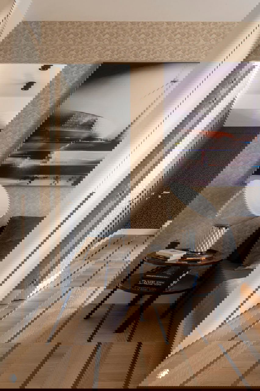 Интерьерная деталь с деревянным паркетом, тёмными хромированными вставками и прикроватной зоной, где текстура паркета создаёт ритм и глубину пространства.