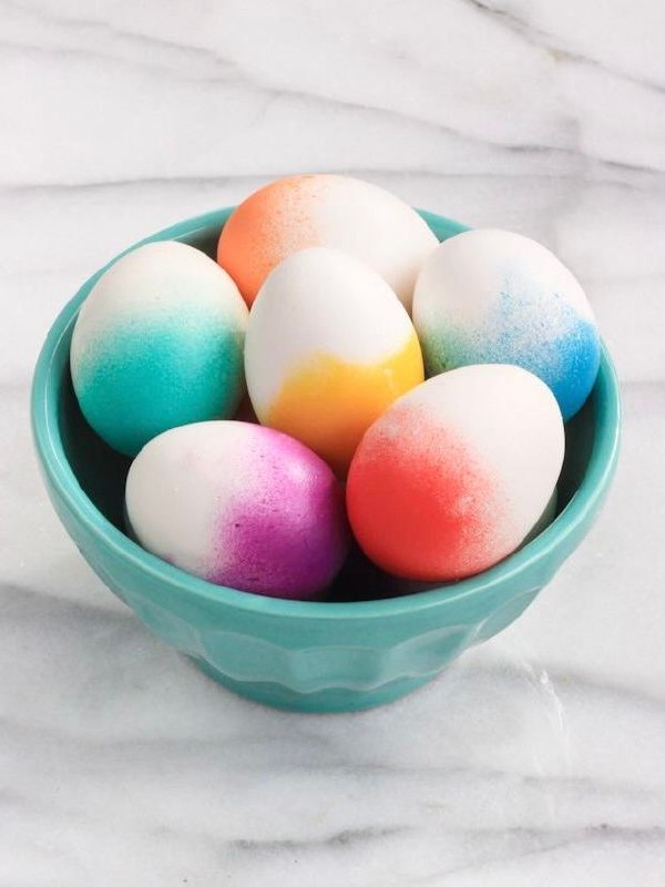 Миска с пасхальными яйцами, окрашенными градиентом и распылением: бирюзово-жёлтые, розовые и голубые переходы на светлом мраморном фоне.