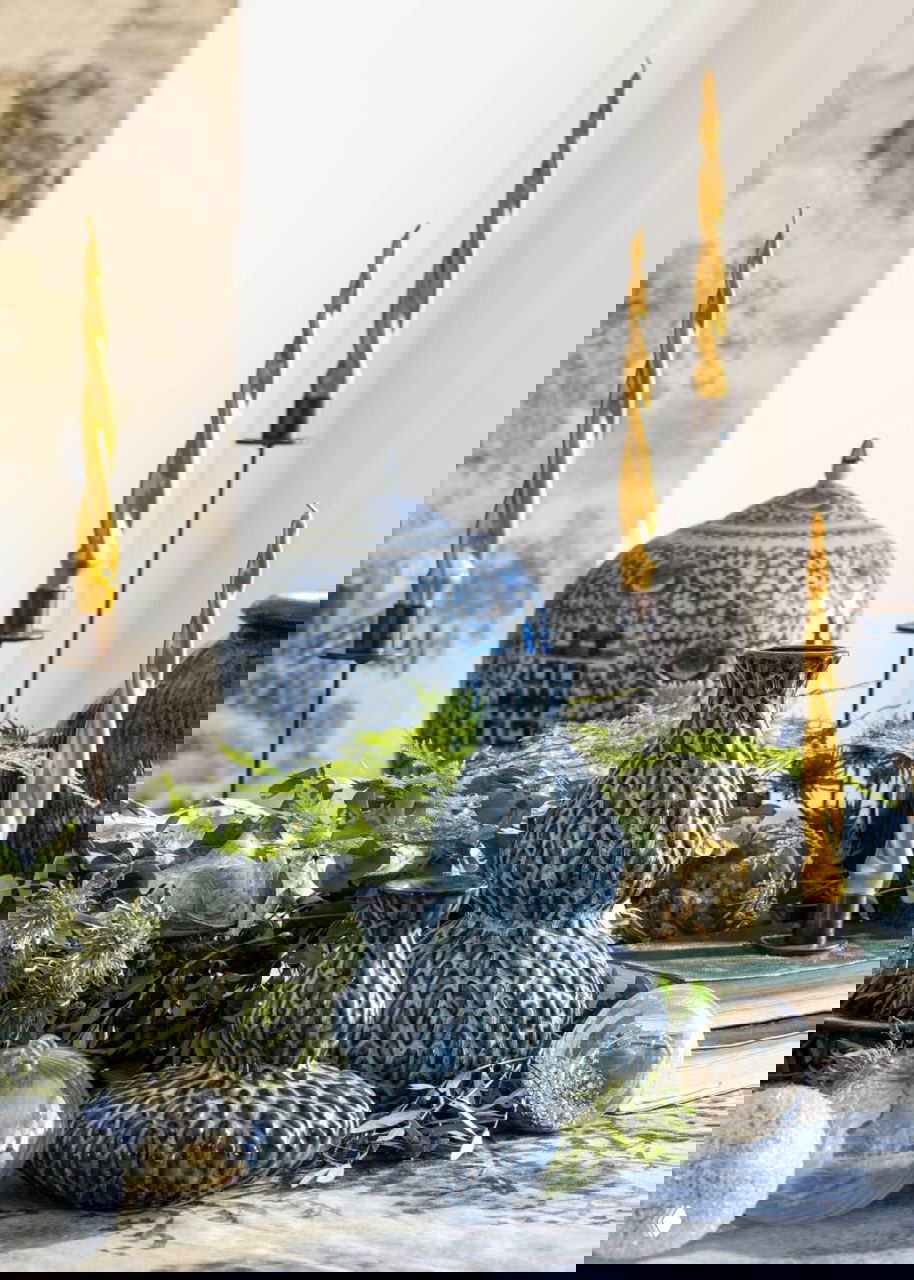 Набор синих декоративных ваз и золотых свечей на фоне растительного декора — акцент на фактурах и сочетании синего с золотом в праздничной композиции.