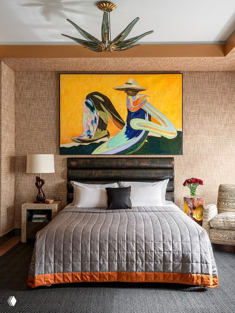 Спальня с большой картиной над изголовьем кровати: спокойная цветовая гамма, стеганое покрывало и декоративные предметы по бокам кровати создают уют.