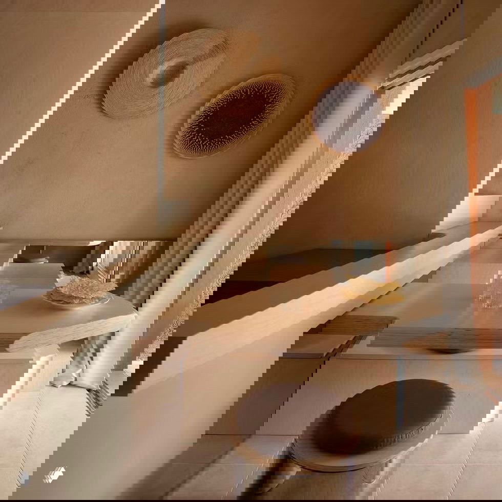 Маленькая столовая зона: деревянный стол, круглый табурет и отражающие поверхности, подчёркивающие морской характер интерьера мини-дома.