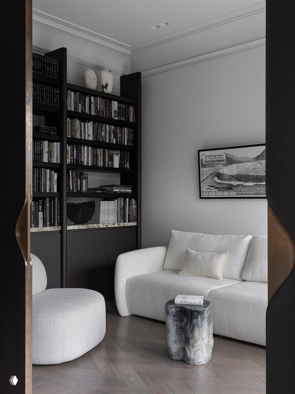 Уютный уголок с тёмным книжным стеллажом, белым диваном и каменным табуретом-столиком (Belousova.Interior, 160 m², Хамовники)