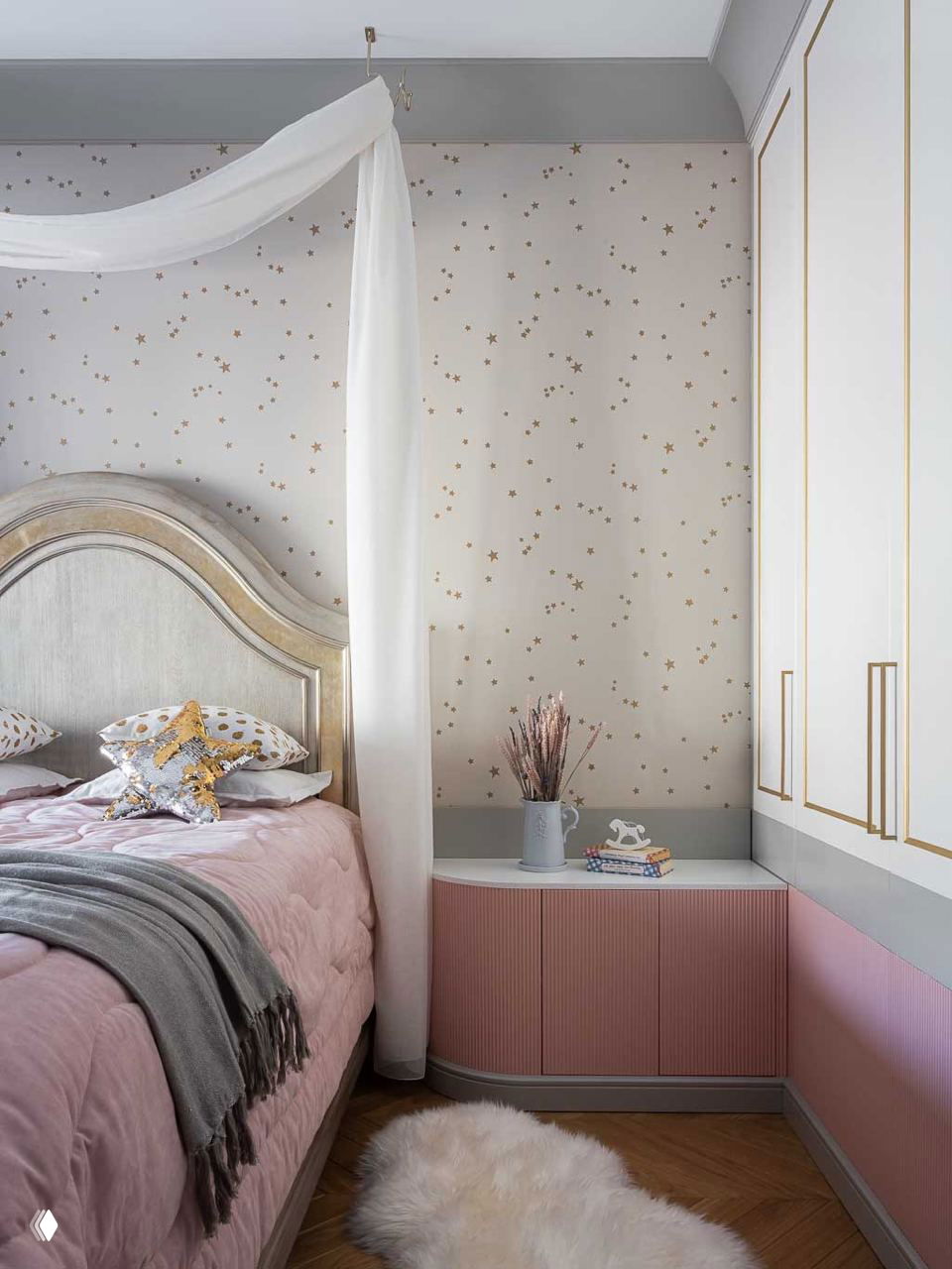 Кровать с высоким изголовьем и воздушным белым балдахином, звёздная фоновая обивка и розовые акценты в текстиле создают уютную атмосферу.