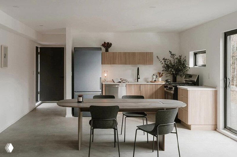 Открытая кухня-столовая в светлой минималистичной палитре: стол, стулья и рабочая зона у окна, фотография содержит цифровые артефакты и фрагменты искажений.