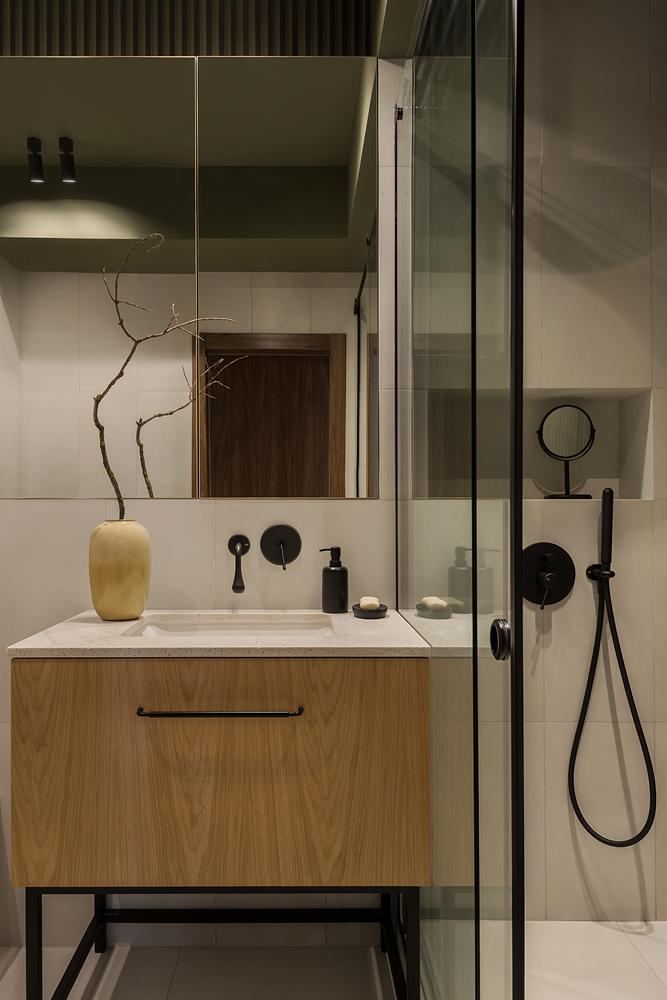 Компактная ванная комната с деревянной тумбой, мраморной столешницей и чёрной матовой сантехникой; лаконичный и уютный дизайн с контрастными элементами.