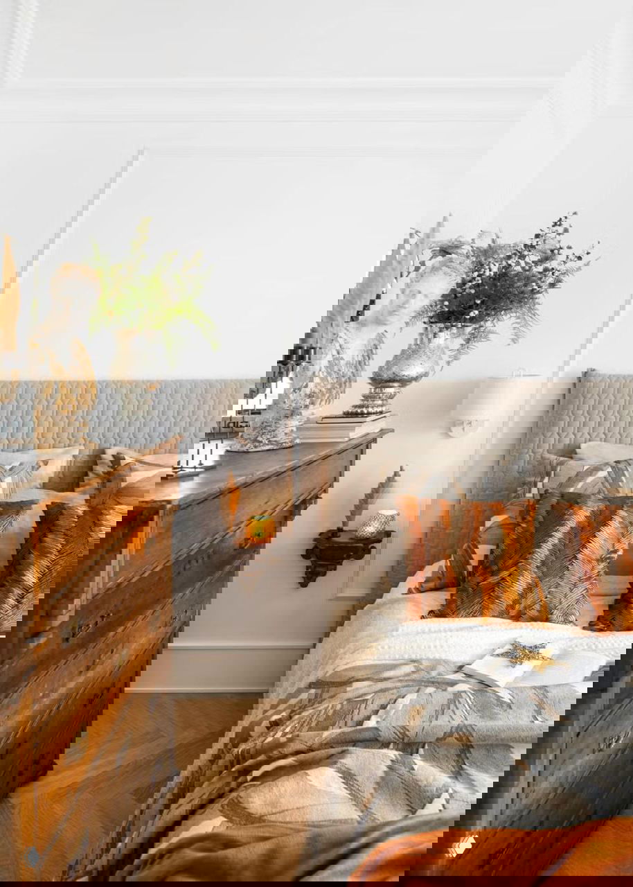 Спальная зона с мягким изголовьем, текстилем и декоративными подушками тёплых тонов — пример замены текстиля для создания праздничной атмосферы.