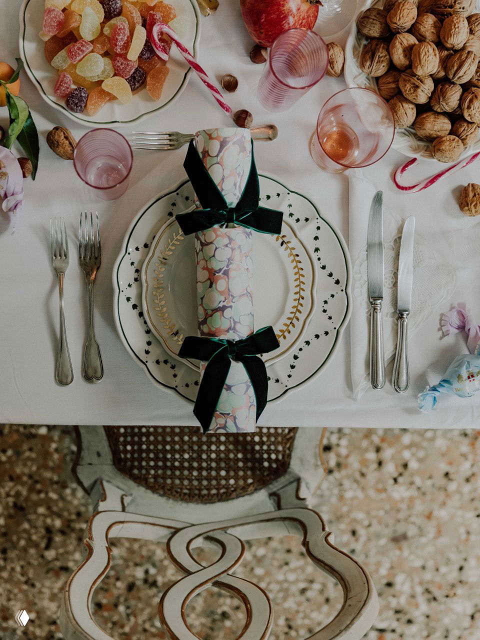 Кадр с сервировкой: тарелки, хрустальная посуда и чаши с мандаринами и сладостями на белой праздничной скатерти в палаццо.