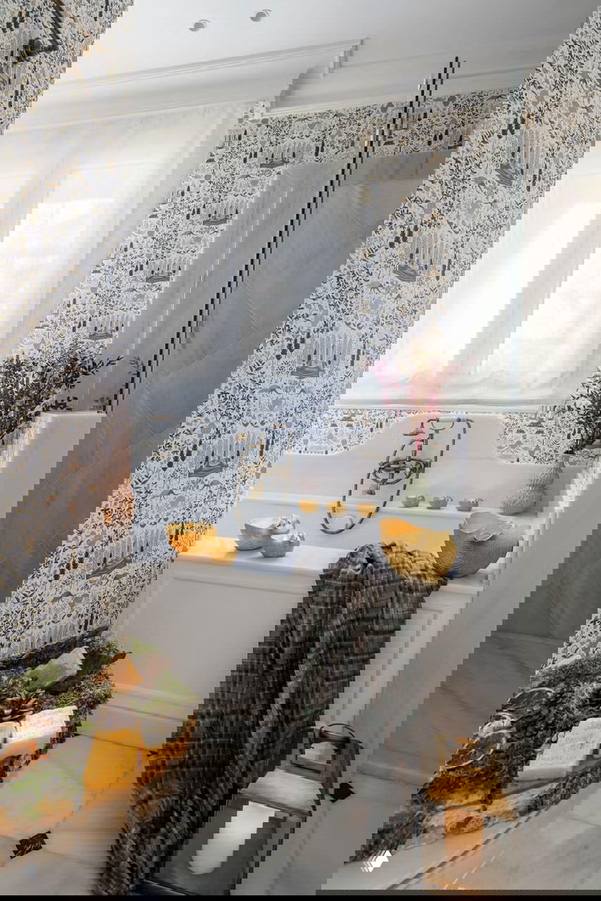 Ванная комната с золотыми аксессуарами и декоративными элементами на фоне узорчатых обоев — неожиданный праздничный акцент в приватной зоне дома.