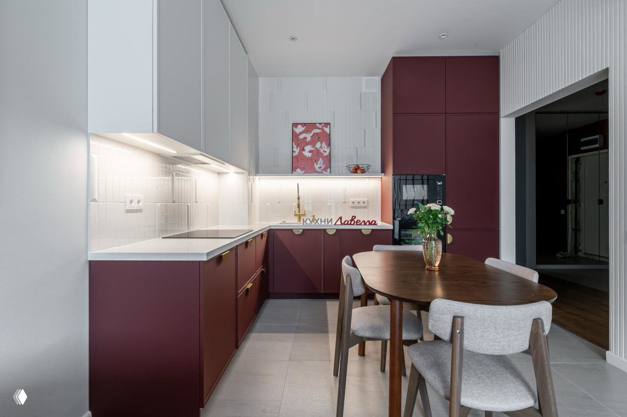 Вид на рабочую зону кухни «Броуди» с интегрированной техникой: белый фартук, подсветка по периметру и высокий винно-бордовый шкаф в глубине пространства, чистые линии дизайна.