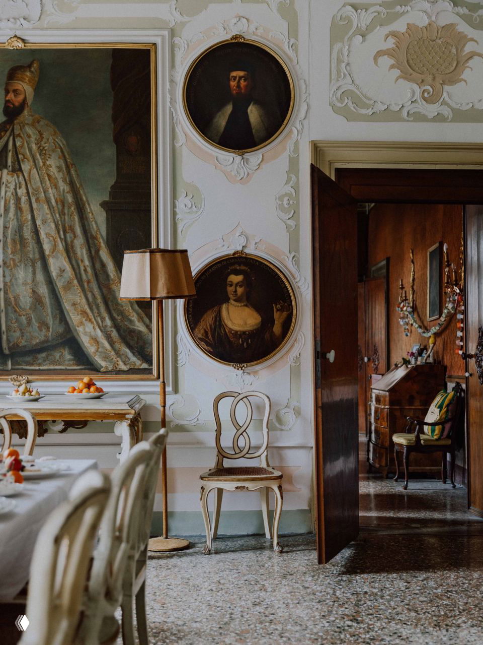 Крупный план места за столом: декоративный праздничный крекер/сценический элемент на тарелке, серебряные приборы и стеклянная посуда.