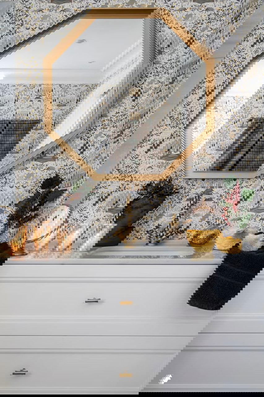 Раковина и зеркало в ванной с золотой рамой, подсвечники и декоративные элементы — внимательная работа над деталями интерьера в рождественском антураже.