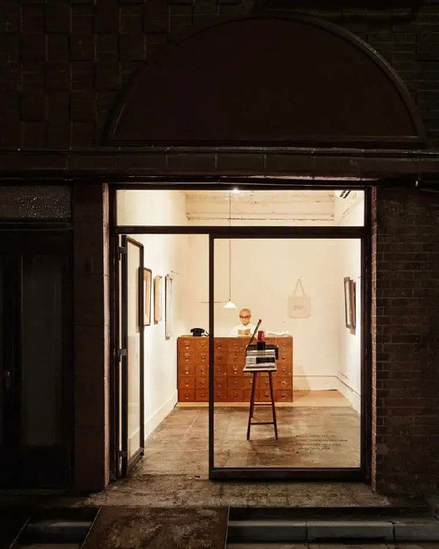 Интерьер книжного со столом и предметами: третье фото содержит визуальные артефакты/глитч, но передаёт атмосферу минималистской экспозиции книги.