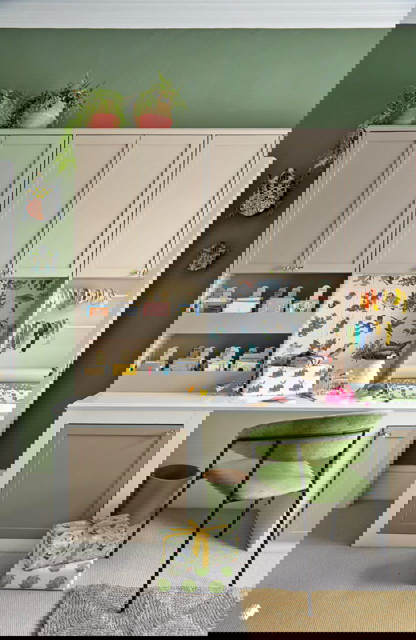 Рабочая зона с бежевыми шкафчиками и зелеными акцентами, аккуратно упакованные подарки и организованное пространство для рукоделия в доме Холли Такер.