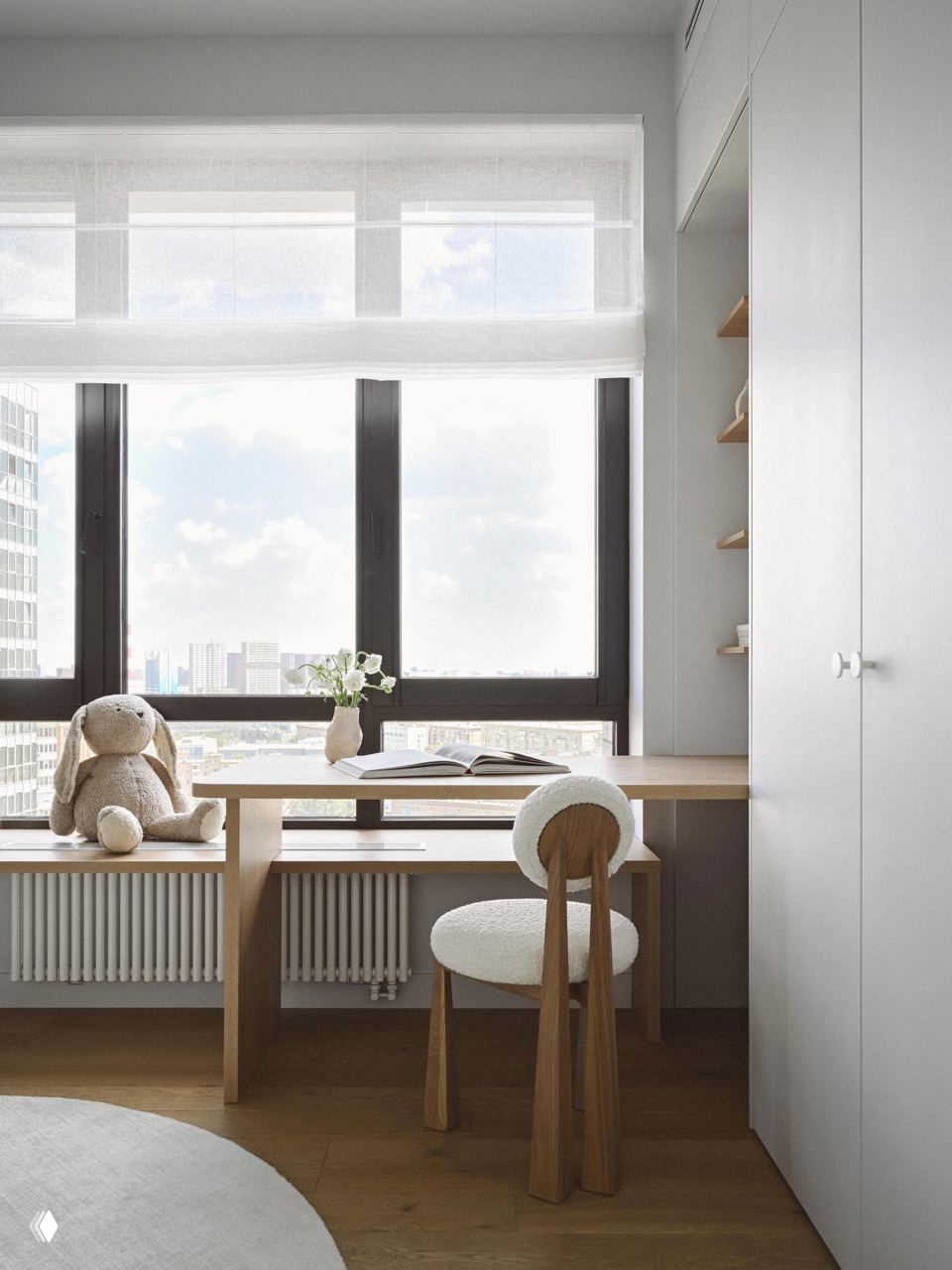 Детская рабочая зона у окна с компактным письменным столом, мягким круглым стулом и игрушкой на подоконнике; светлая и организованная ниша для занятий.