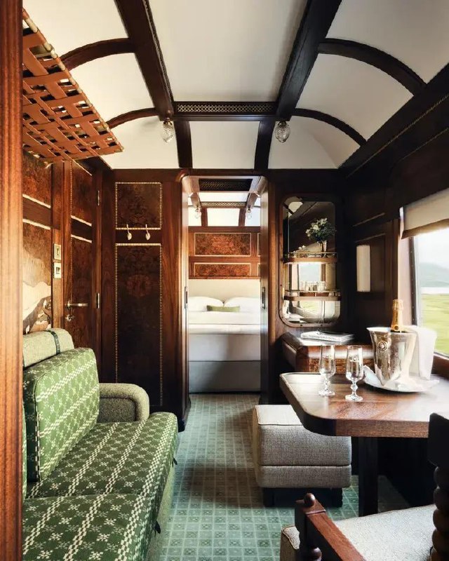 Интерьер купе Royal Scotsman: зеленая узорчатая обивка, деревянная столешница и сервировка с шампанским и бокалами на столике у окна