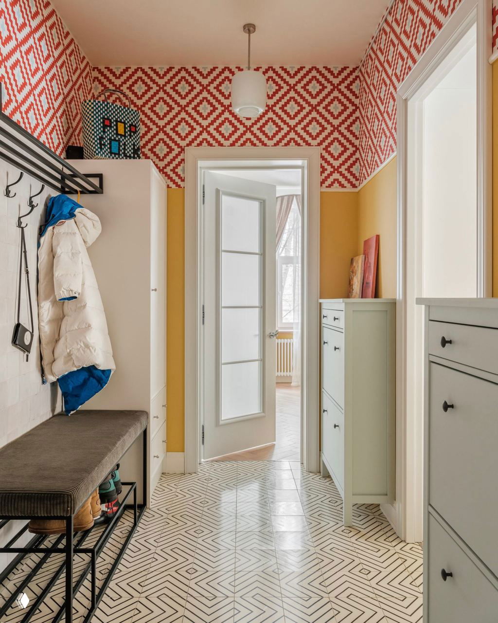 Яркий коридор с этническим орнаментом на стенах и чётким геометрическим рисунком пола; сочетание жёлтых и красных акцентов в интерьере.