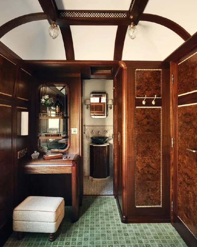 Туалетный столик и небольшая ванная зона в сьюте поезда с панелями из красного дерева и зеркалом над раковиной, детальная отделка маркетри
