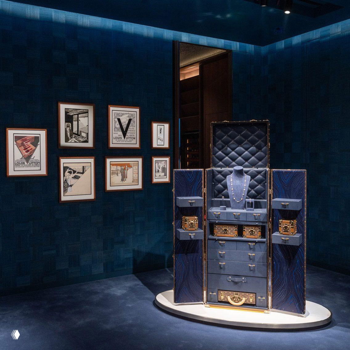 Интерьер бутика Louis Vuitton: витрина с экспозицией и интерьерные элементы в синих тонах, акцент на предметах бренда и оформлении.