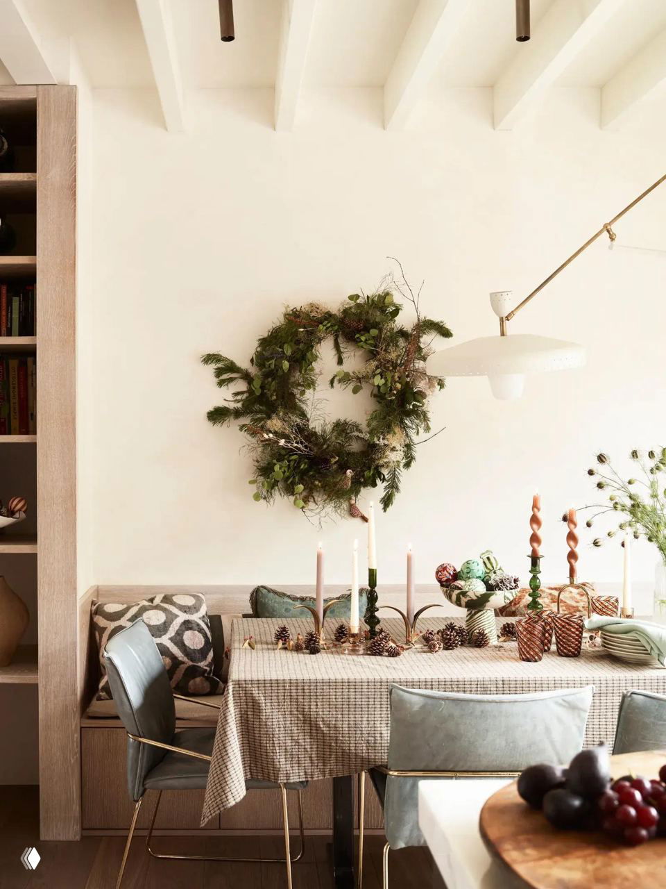 Стильная минималистичная сервировка: венок на стене, подсвечники и лёгкий декор над столом в небольшом столовом уголке