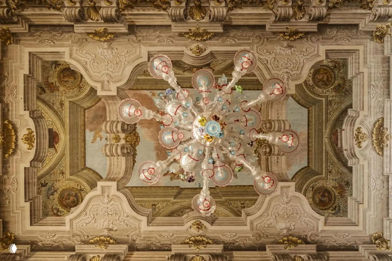 Украшенный потолок с большой венецианской люстрой и фресками в залах палаццо Пизани Моретта — историческая архитектурная отделка будущего фонда.