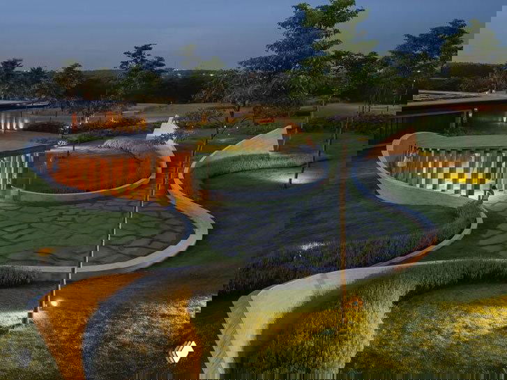 Извилистая дорожка между криволинейными бетонными стенами, которая ведёт к капелле; акцент на пути как части архитектуры и ландшафта.