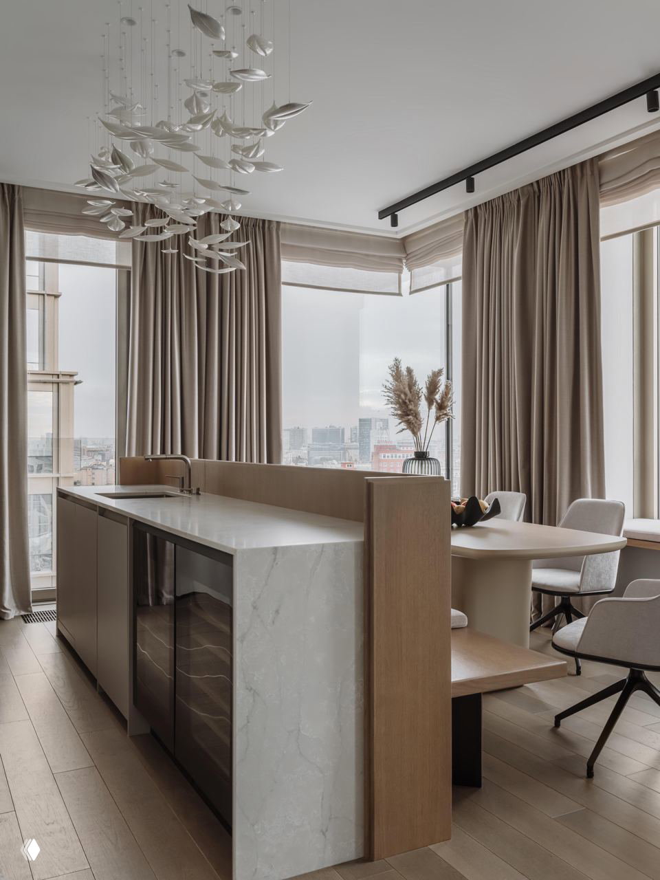 Кухня‑гостиная с островом: мраморная столешница, деревянные вставки и обеденная зона у окна в минималистичной нейтральной палитре интерьера.