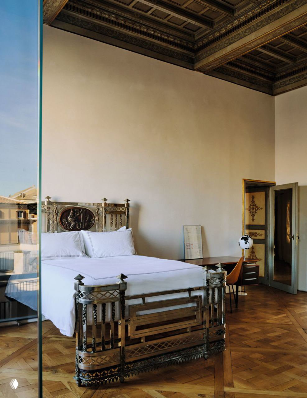 Спальня в палаццо Боргезе: высокая лепнина на потолке, декоративное металлическое изголовье кровати и светлый паркет.