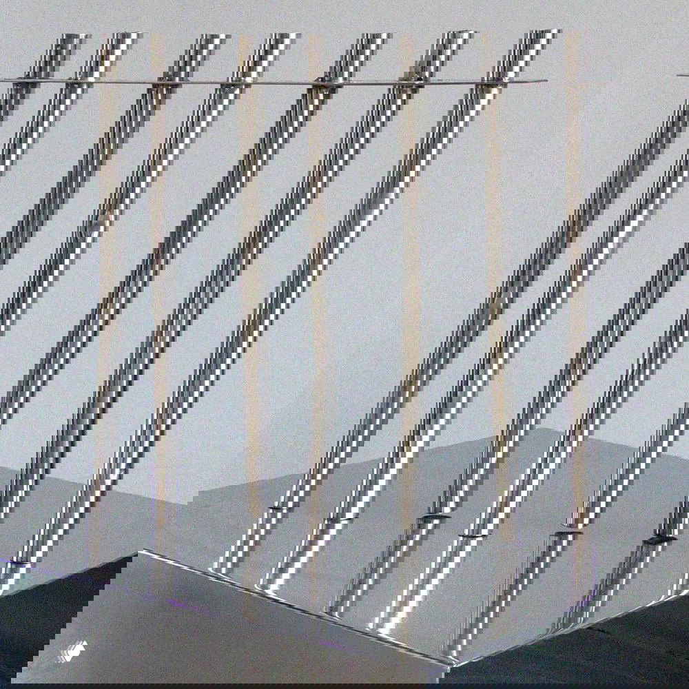 Крупный план стального подсвечника с семью вертикальными стержнями; отражающая сатинированная поверхность и игра света на металле.