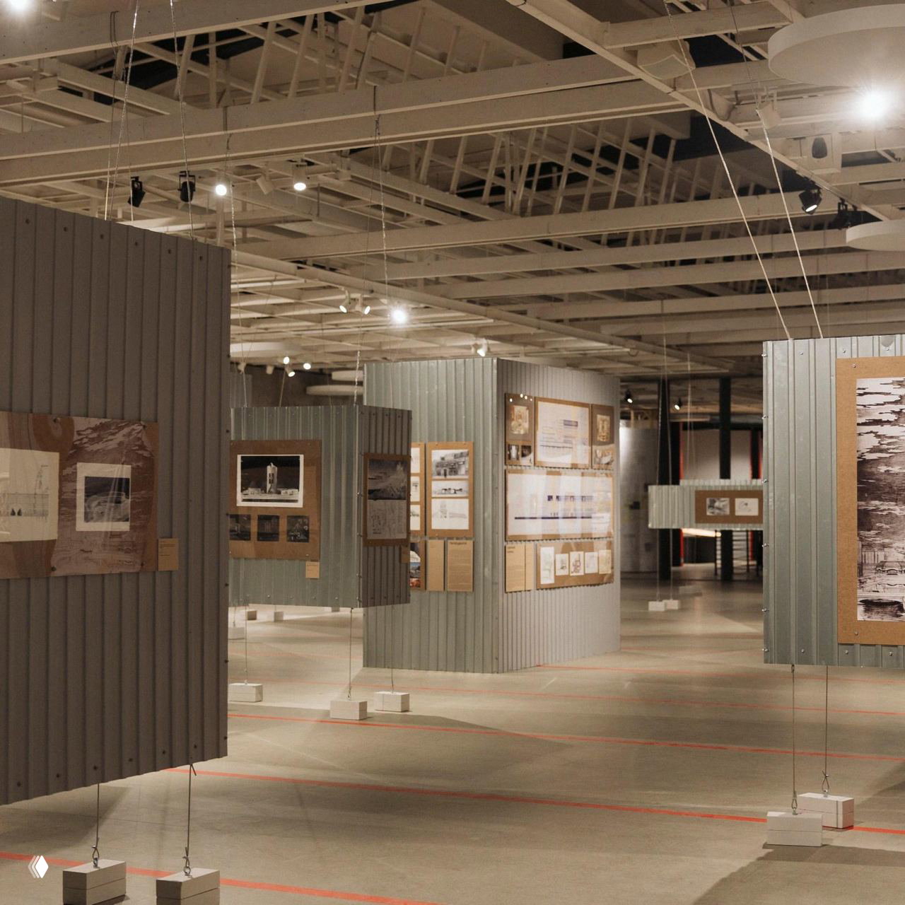 Выставочные модули и подвесные панели в просторном зале Манежа: вид на организованные стенды, освещение и пространственную планировку экспозиции.